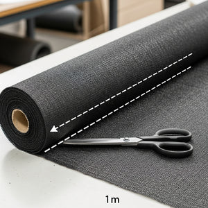 Roll of black shade cloth fabric with a pair of scissors on a white surface