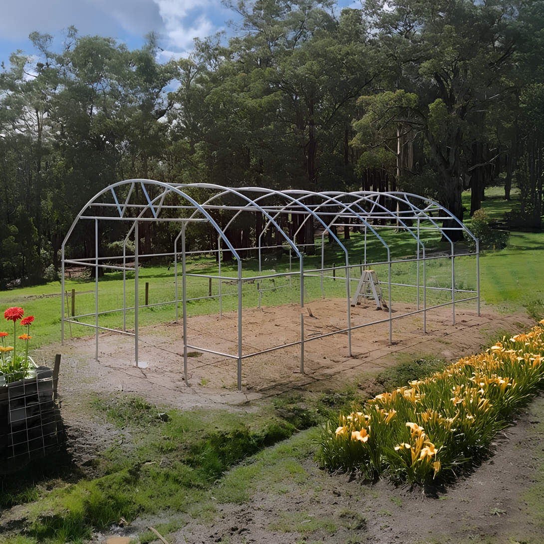 polytunnel  structure fram in a garden with flowers and trees in the background