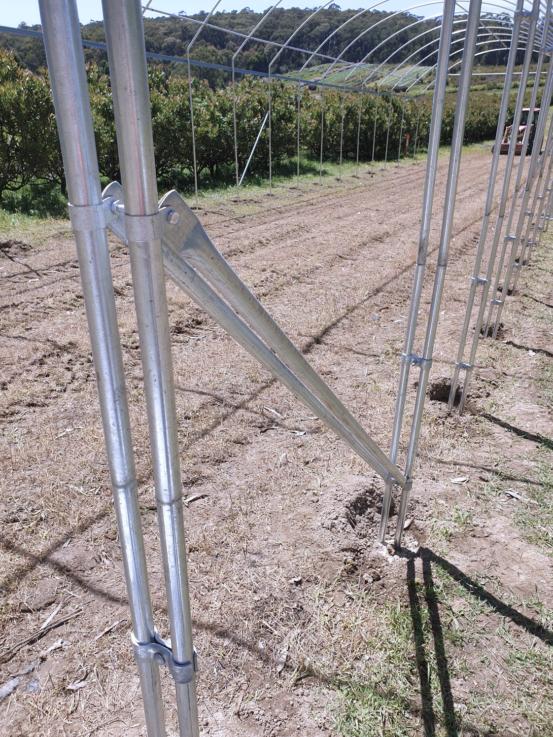 Metal agricultural frame in a field with trees in the background